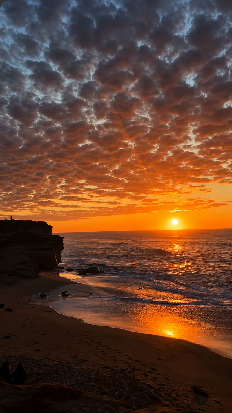 Atardecer en la playa junto a un acantilado